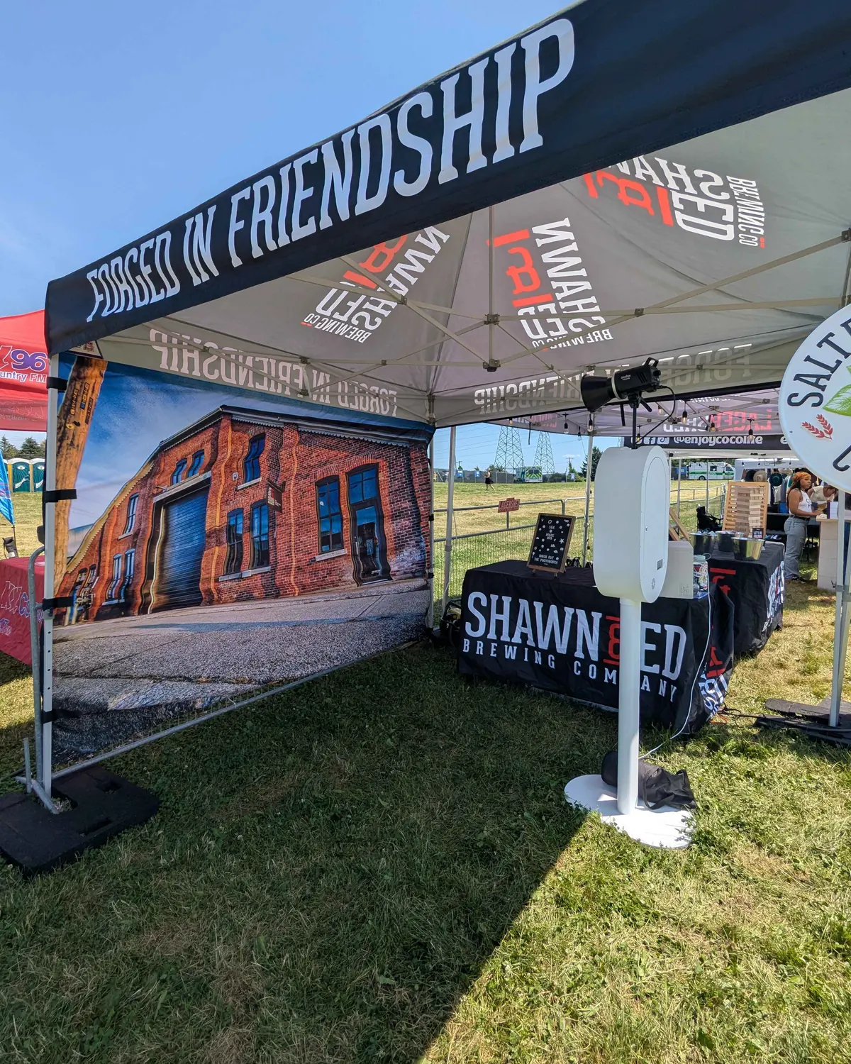 The same custom-printed brick wall backdrop seen from across the marquee, with the booth set up in front of it