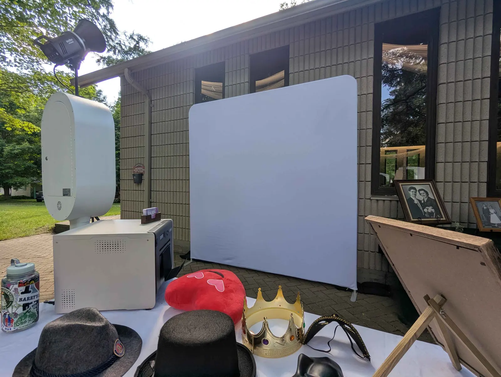 The Aura open-air booth, printer, prop table and white studio backdrop set up outdoors at a wedding