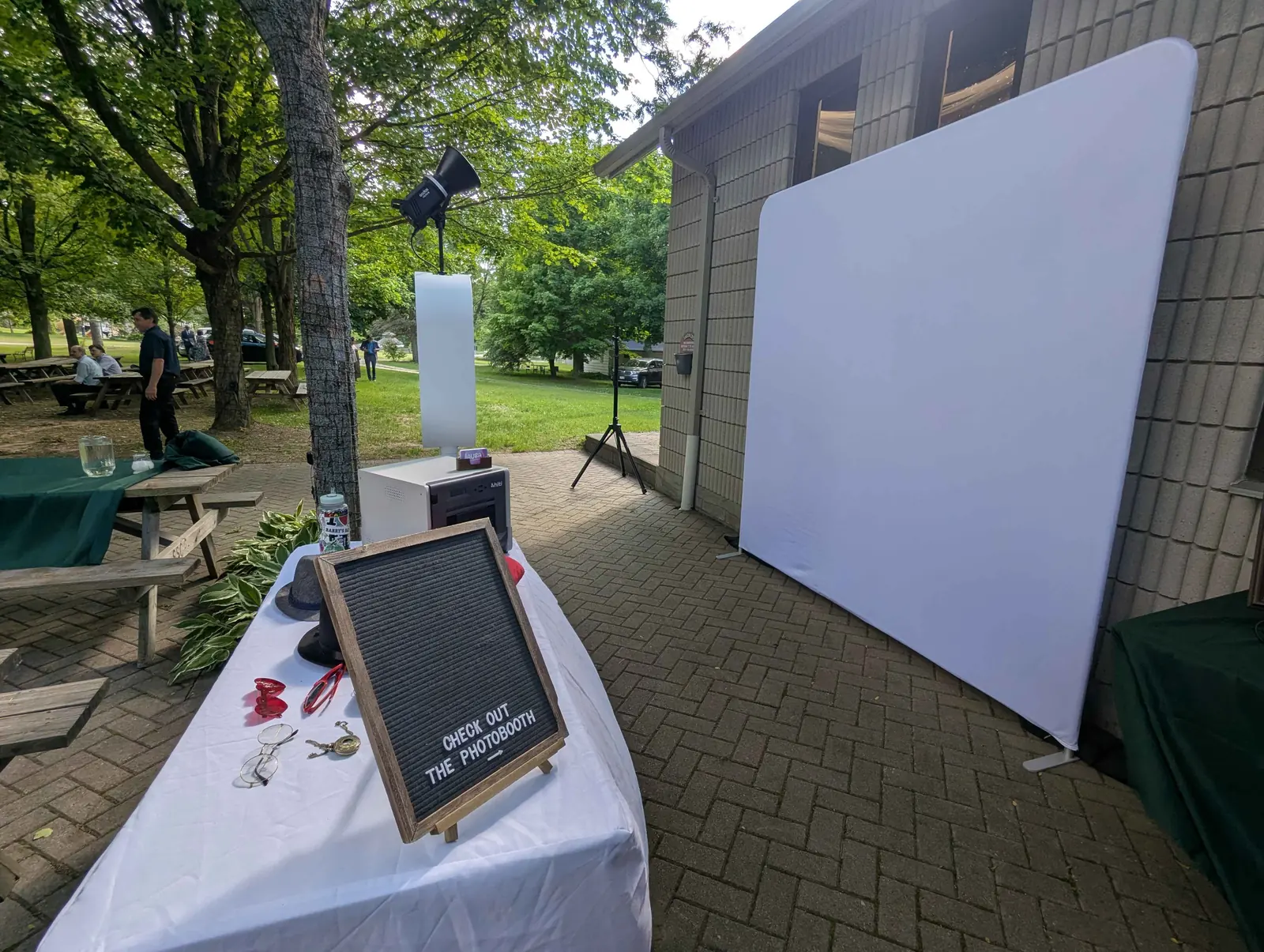 The clean white studio backdrop and the Aura booth set up beside a prop table at an outdoor wedding