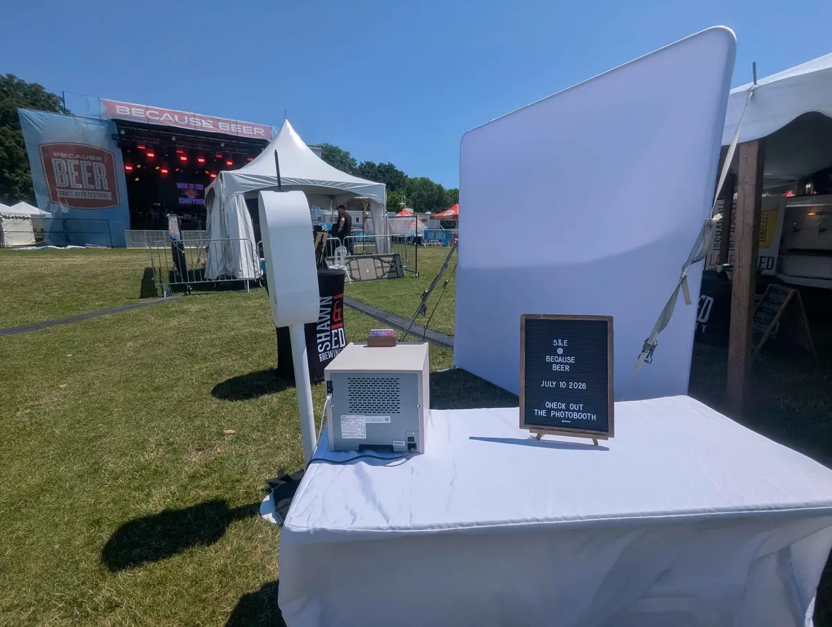 The Aura booth and white studio backdrop set up beside the main stage at the Because Beer craft beer festival