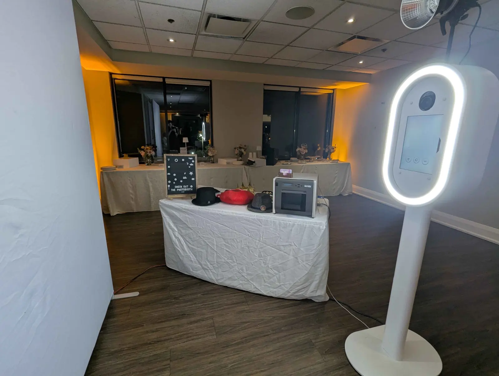 The Aura booth with its ring light on, beside a prop table in a wedding venue at night