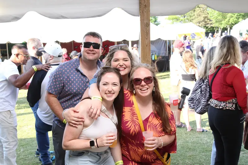 Four friends smiling together at an outdoor party