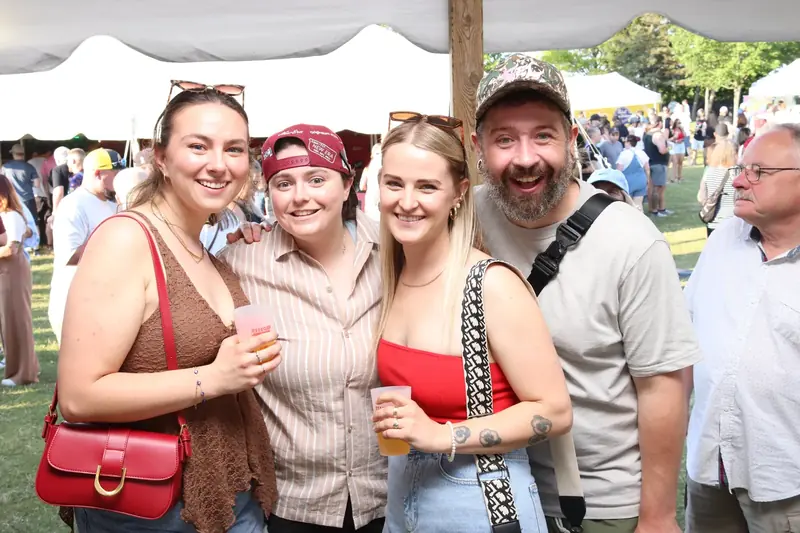 Four friends smiling together at an outdoor party