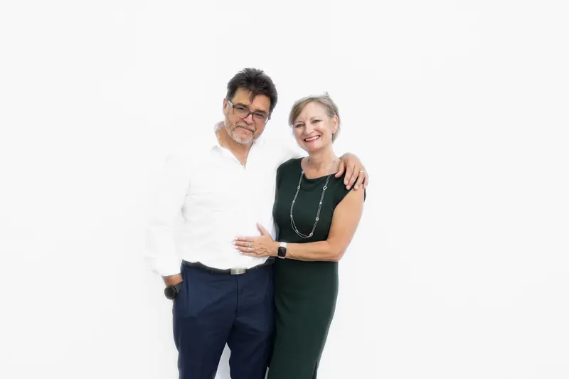 A couple in formal wear smiling together in the Aura photo booth