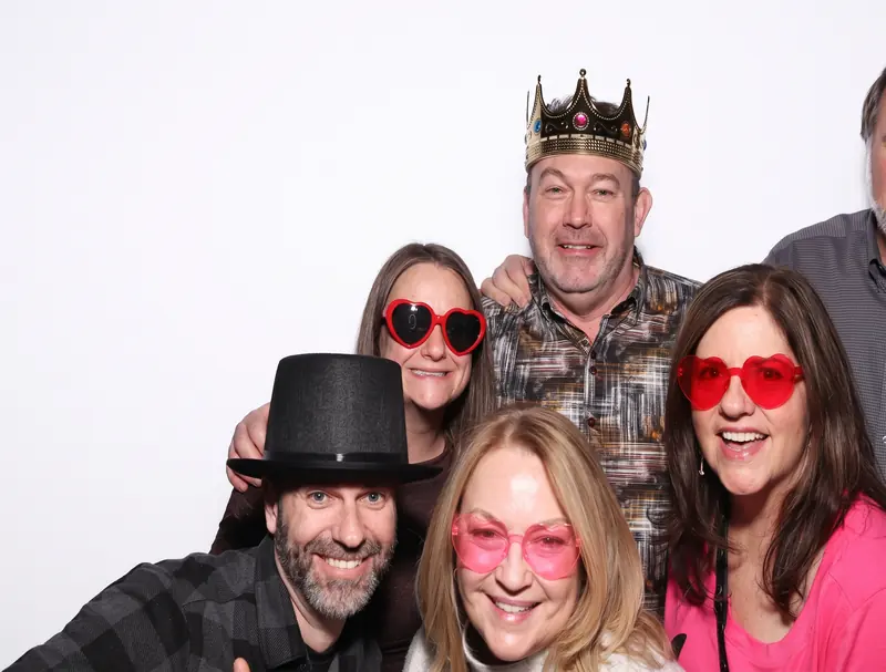 A group of five guests crowded into the Aura booth with party props