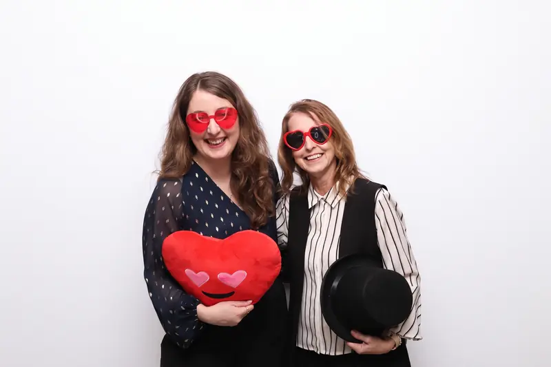 Two guests with a heart prop in the Aura photo booth