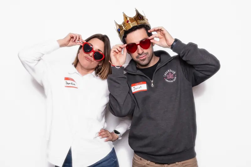Two colleagues wearing event name tags posing in the Aura photo booth