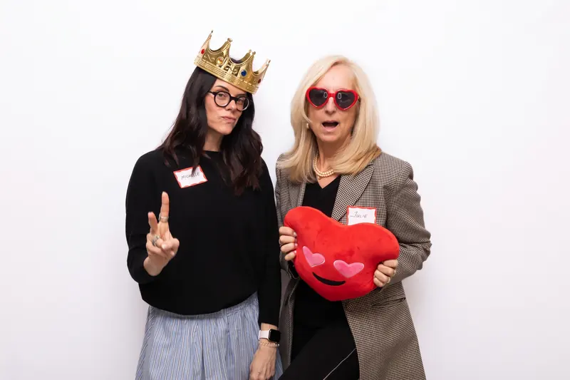 Two guests with event name tags holding a prop in the Aura photo booth