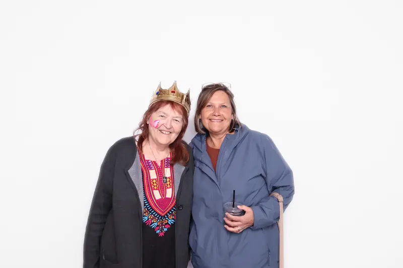 Two volunteers wearing name tags smiling in the Aura photo booth