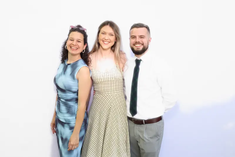 Three guests in formal wear posing together in the Aura photo booth